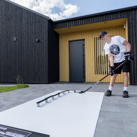 Young hockey player stickhandling on a training pad in the garden, practicing between ice sessions