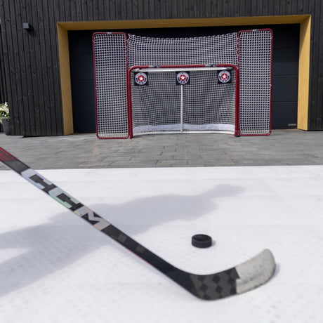 Hockey player on Better Hockey training tiles with a shooting setup including goal and targets in a garden