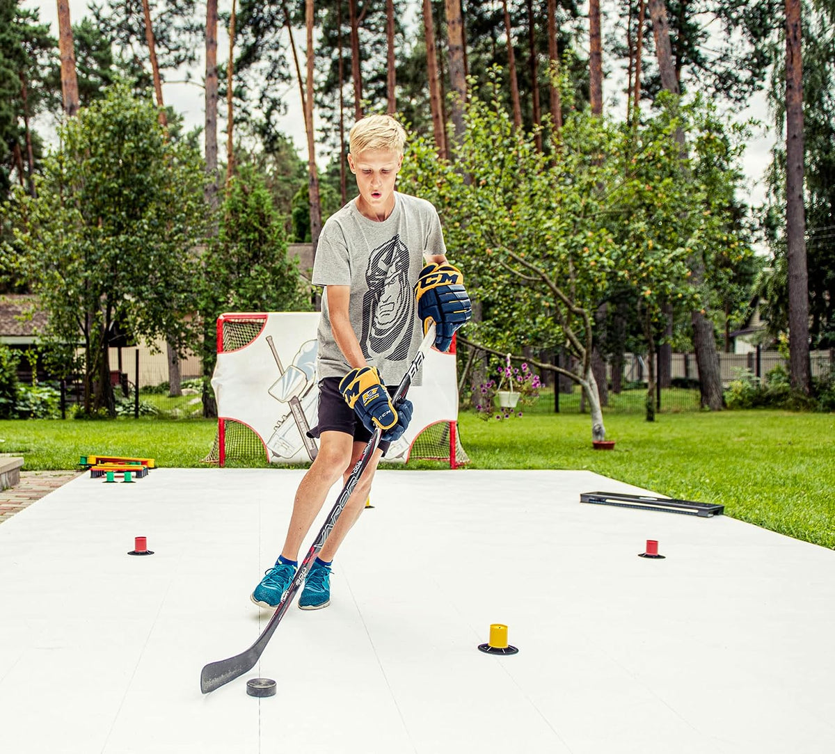 Teen hockey player stickhandling around drill cones on outdoor flooring tiles during a skill practice session