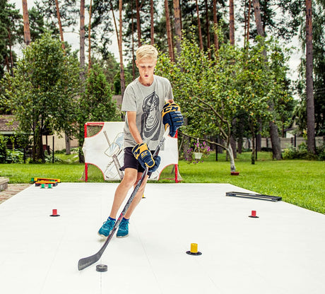 Teen hockey player stickhandling around drill cones on outdoor flooring tiles during a skill practice session
