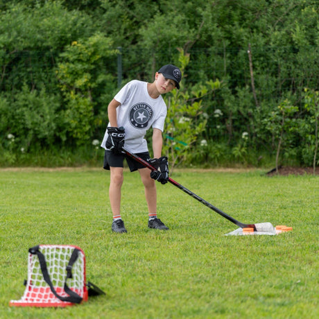 Young hockey player practicing saucer pass with Sauce Combo launch pad and catcher in a garden