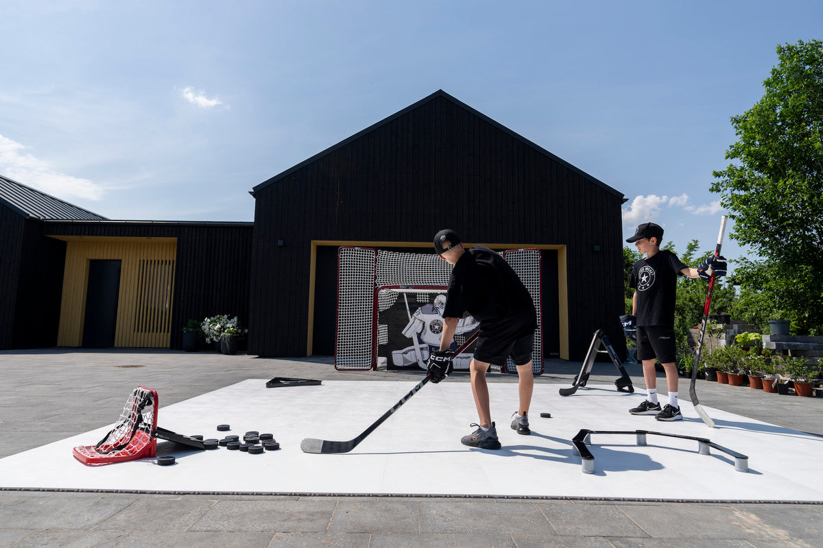 Two players training shooting and passing on flooring tiles in front of a garage